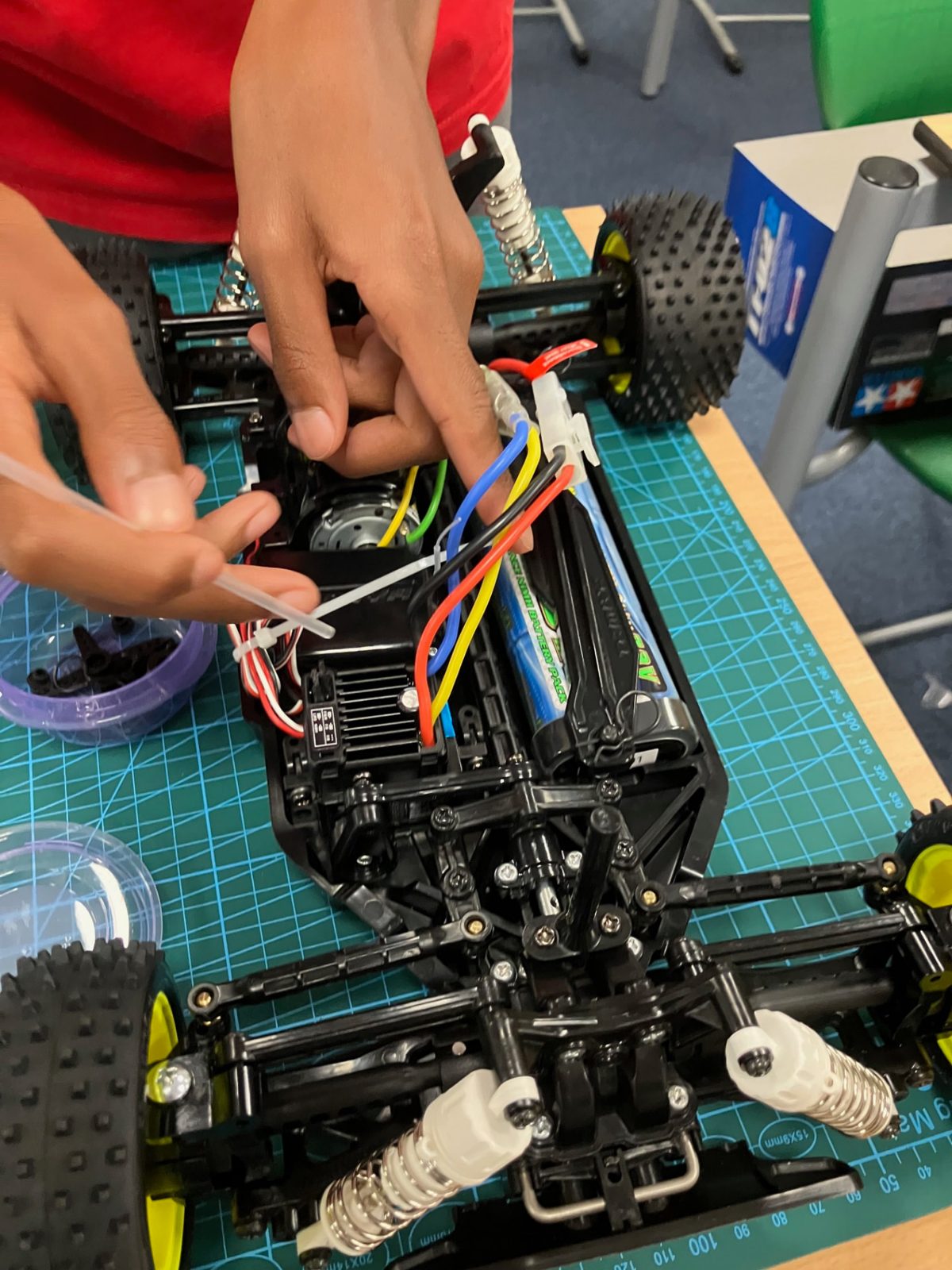 Student wiring the ESC and battery on a Tamiya TT-02 chassis at RC Garage Vienna