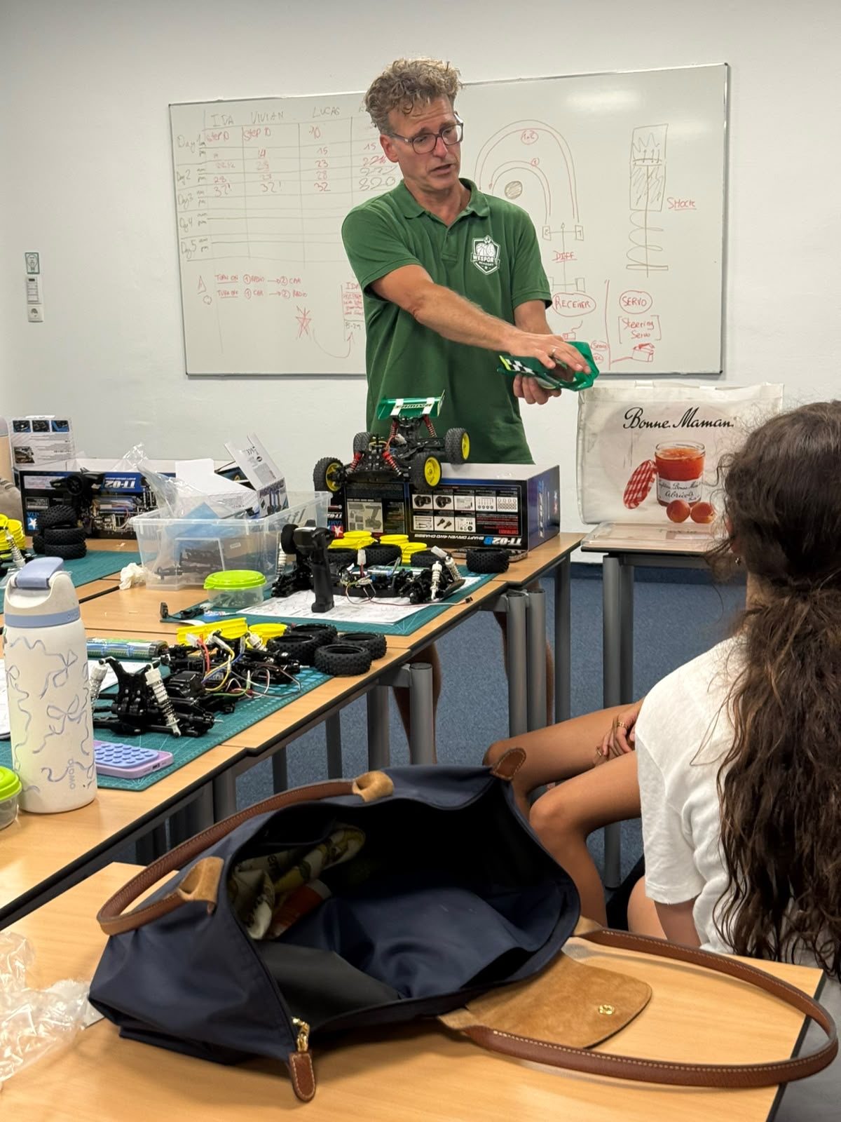 Coach explaining an RC car battery pack to a participant at RC Garage Summer Camp Vienna